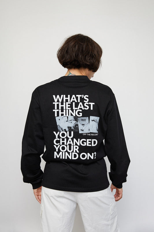 Female model Danielle wearing the "CHANGE YOUR MIND" T-Shirt in unisex size Small and the color black. Danielle has her back to the camera. There is a graphic print on the back that says "What's the last thing you changed your mind on?" in white text paired with four black-and-white photographs.